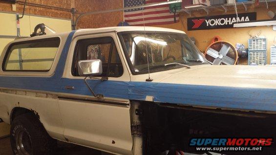 White and blue 1978 Ford Bronco with blue tape on the fender and door