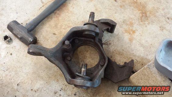 Steering knuckle assembly with a hammer and nut on a concrete surface
