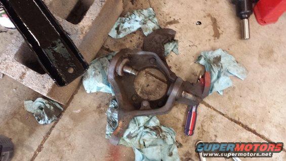 Vehicle spindle assembly with grease and rags on concrete floor