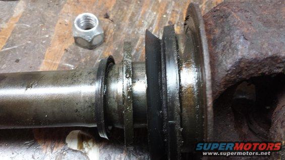 Close-up of a greasy automotive part with a nut nearby