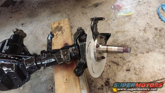 Close-up of a vehicle's front axle with brake rotor and hub assembly