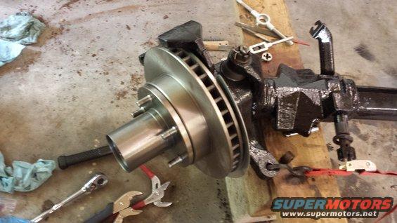 close-up of a vehicle's front axle assembly with brake rotor and caliper components