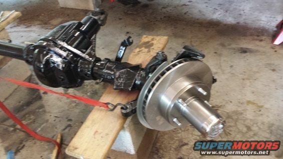 Front axle assembly with disc brake rotor and caliper bracket, supported by wooden blocks