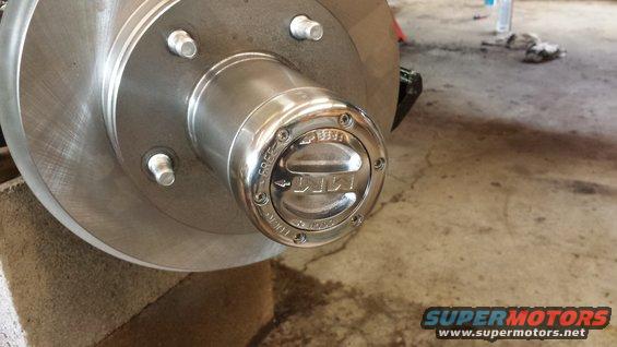 Close-up of a shiny metal hub with a "4x4" logo and "FREE" and "LOCK" indicators. A brake rotor is visible to the left