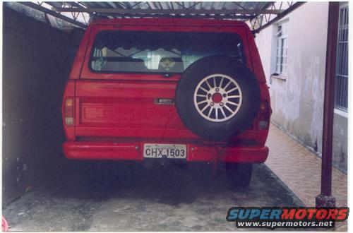 Red pickup truck's rear end with a spare tire on the tailgate. License plate reads CHX 1503