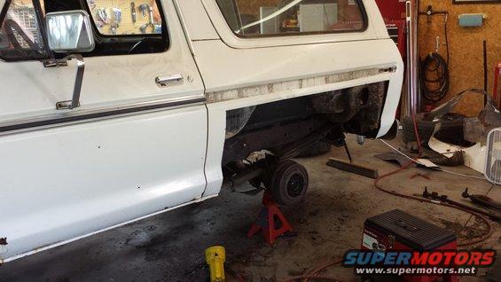 White 1978 Ford Bronco side view, rear axle removed and supported by jack stands in a garage