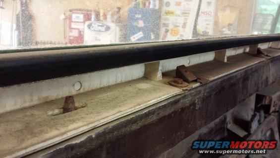 Interior window frame with rusty fasteners and a black rubber seal