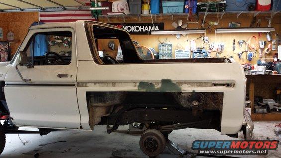White 1978 Ford Bronco body on jack stands in a garage, with the rear section removed