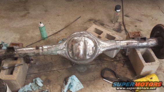 Rear axle assembly on cinder blocks, with spray can and rags nearby