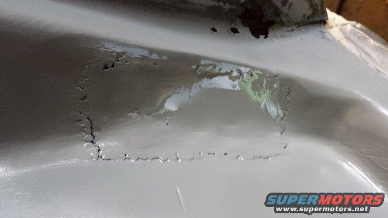 close-up of rust holes on a car's body panel, possibly under repair