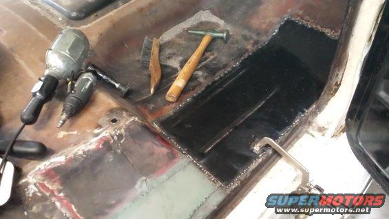 Tools and freshly welded metal patches on a vehicle's floor pan