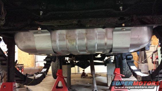 Underside view of a vehicle on jack stands, showing the fuel tank and suspension components
