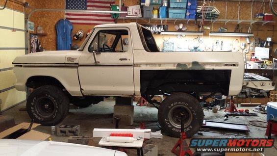 White 1978 Ford Bronco on jack stands in a garage, undergoing work
