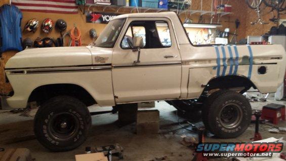 White 1978 Ford Bronco lifted on blocks in a garage, undergoing repairs