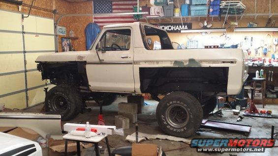 1978 Ford Bronco in a garage, missing front fenders and hood, on jack stands