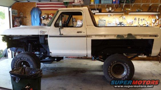 White 1978 Ford Bronco in garage, missing front fenders and hood, side view