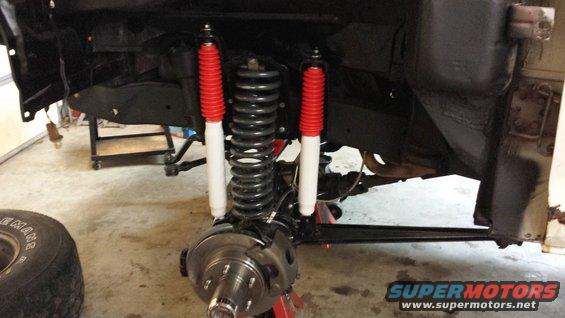 Front suspension assembly with new red and white shock absorbers and coil springs. Disc brake rotor visible