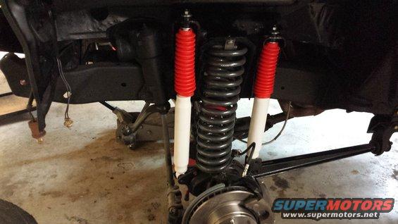 Close-up of front suspension with red-cased shocks and coil springs
