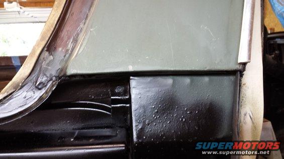 Close-up of a black painted vehicle body panel with some texture and a light green panel above it