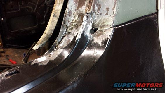 Close-up of rusted metal panel repair with visible welds and grinding marks