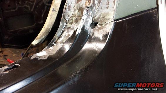 Close-up of rusted metal panel being repaired with welds and grinding marks