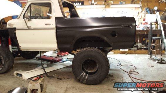 1978 Ford Bronco body with black rear quarter panel and white cab, undergoing repairs