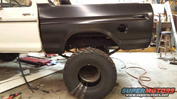 White and black 1978 Ford Bronco rear quarter panel, lifted, with large tire