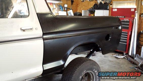 Side view of a white and black Ford Bronco with a black rear quarter panel, possibly undergoing restoration