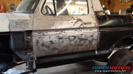 1978 Ford Bronco side view, primer and rust on driver's door, black rear quarter panel