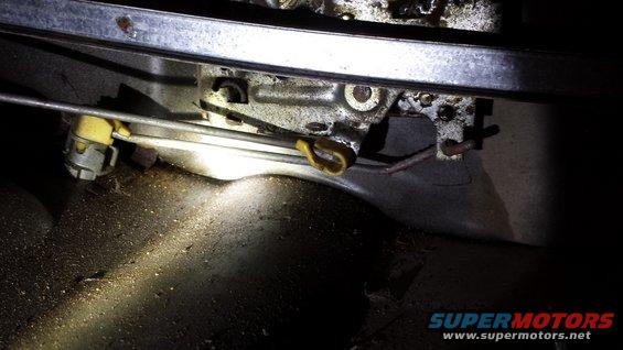 Close-up of a car's interior door latch mechanism with cables and yellow plastic parts