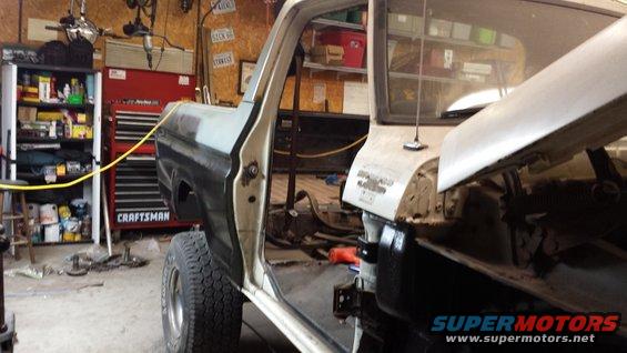 Open door of a disassembled truck showing interior and engine bay