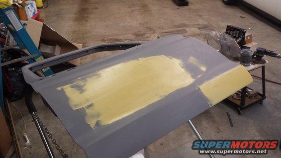 Car door with yellow body filler applied to the exterior surface, angled view