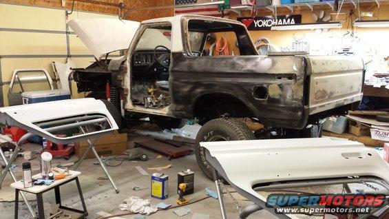 1978 Ford Bronco in a garage, undergoing bodywork with hood and doors removed