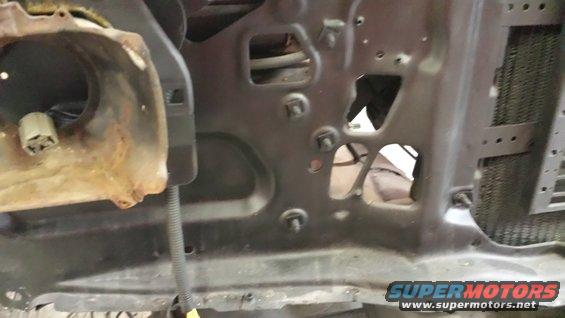 Close-up of a vehicle's inner fender area, showing rusty metal and mounting points