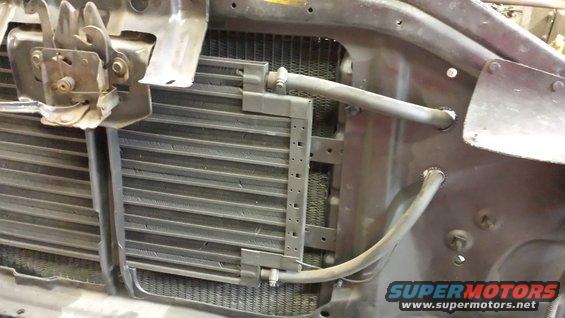 Radiator and condenser assembly with hoses and hood latch mechanism