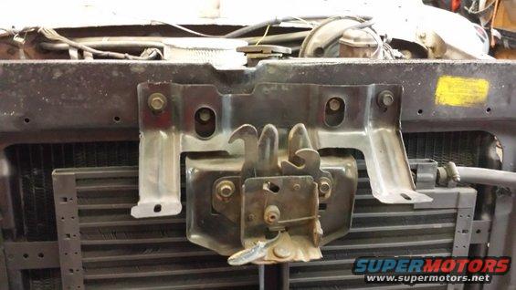 Hood latch mechanism mounted above a radiator