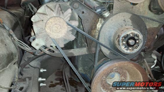Engine alternator with fan blades and drive belts connected to pulleys