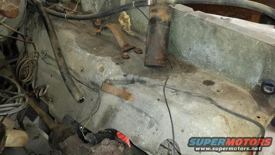 Engine bay with hoses, wires, and rusty metal brackets