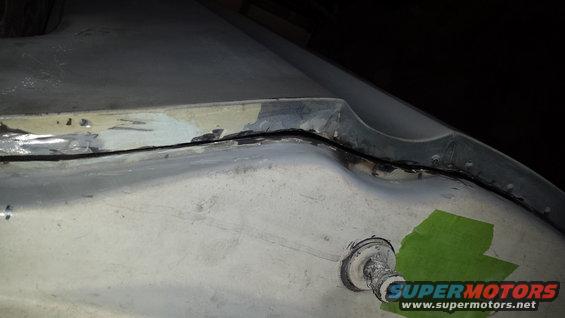 Damaged body panel seam with green tape and Supermotors logo