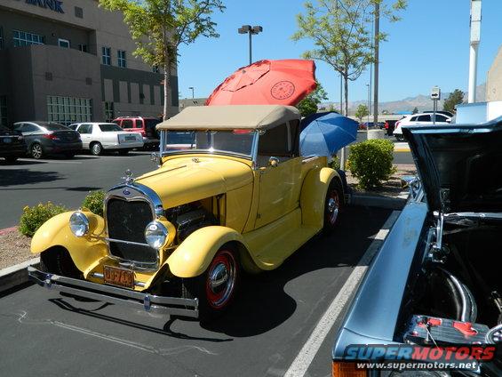 Yellow 1928 Ford Model A convertible parked next to another car with hood open