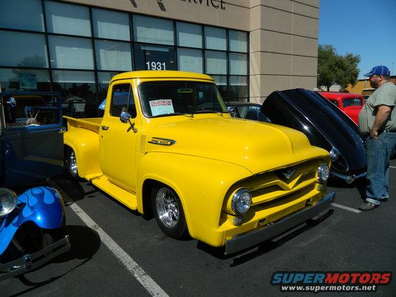 Yellow 1956 Ford F-100 pickup truck parked next to other vehicles