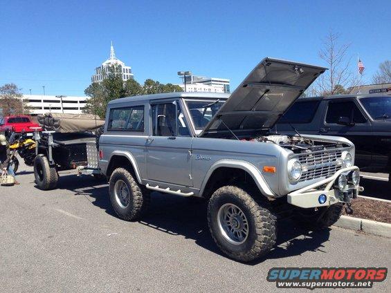 Silver 1979 Ford Bronco with hood open, towing a trailer