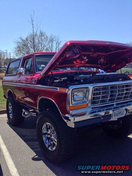 Red 1979 Ford Bronco with hood open, showing chrome grille and license plate BDAPPLE