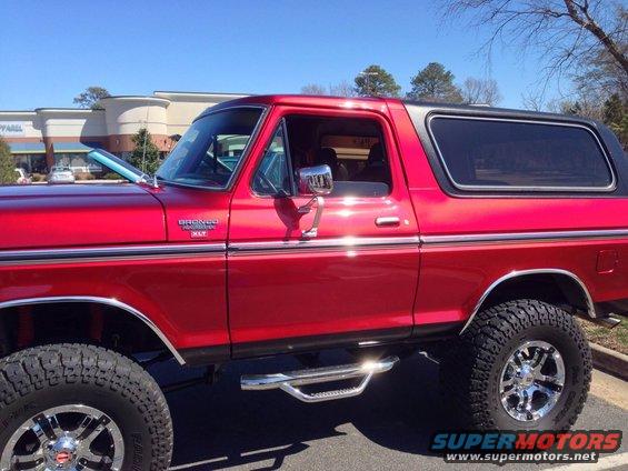 Red 1979 Ford Bronco side view with chrome wheels and side steps
