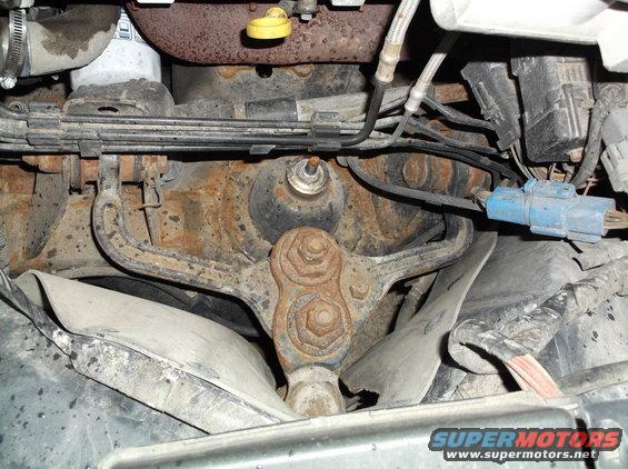 Rusty engine parts and suspension components with a blue electrical connector