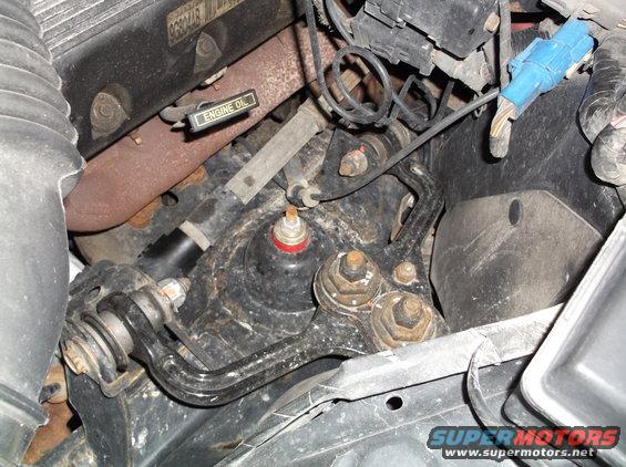 Engine bay with rusty exhaust manifold, oil dipstick, and suspension components