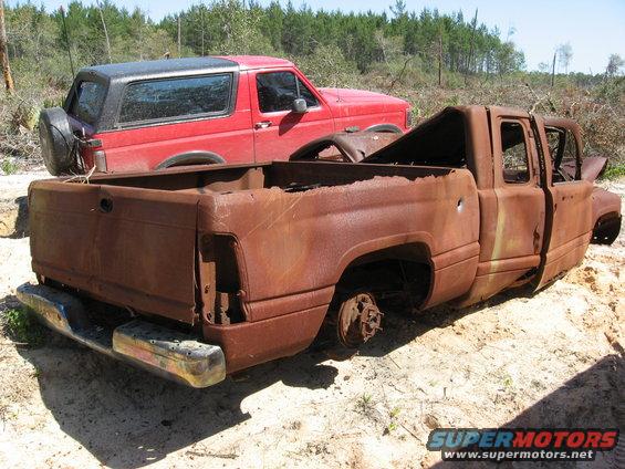 Red 1994 Ford Bronco with black top and spare tire, seen from the rear 3/4 view