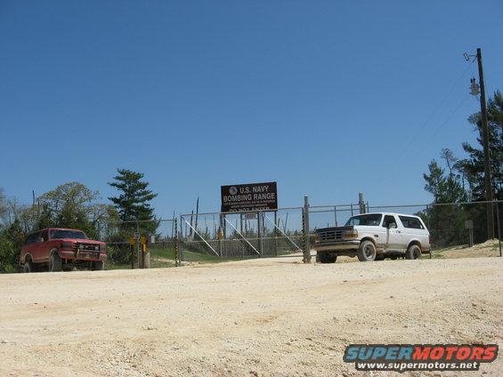 1992 Ford Bronco parked next to a red Ford Bronco at a U.S. Navy Bombing Range entrance
