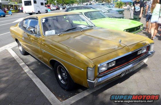 Gold sedan parked on pavement, front quarter view. Visible grille, headlights, and license plate GP 1743