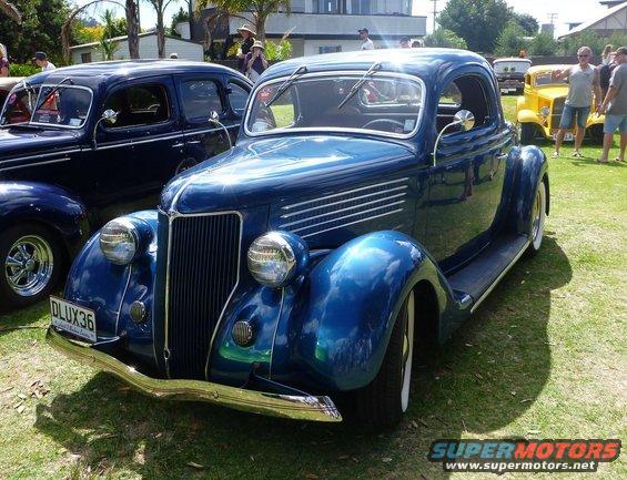 Blue coupe with chrome grille and whitewall tires. License plate DLUX36